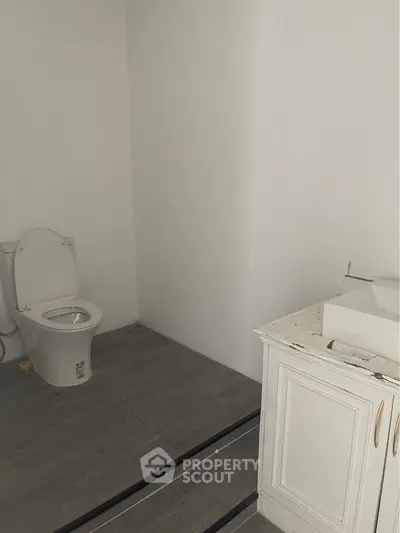 Minimalist bathroom with modern toilet and white vanity in a sleek design.