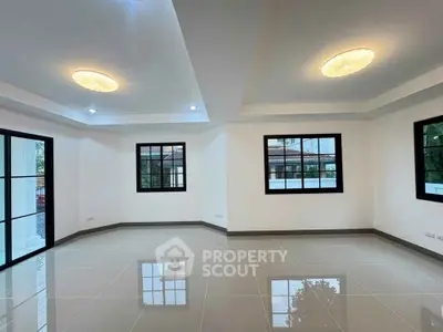 Spacious modern living room with large windows and elegant ceiling lights.