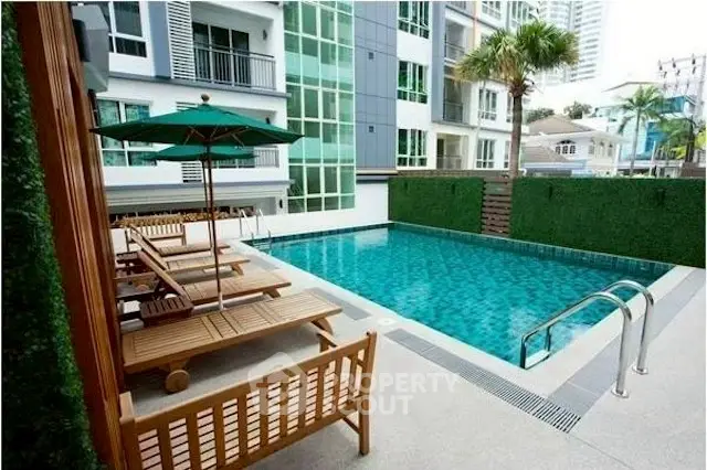 Luxurious condominium pool area with sun loungers and modern design, perfect for relaxation.