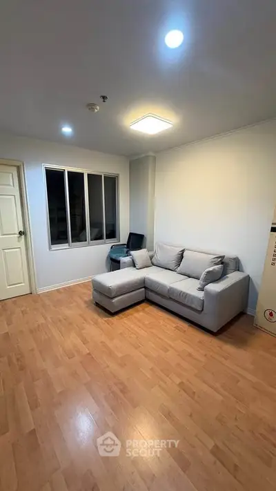 Cozy living room with modern gray sofa and wooden flooring, perfect for relaxation.