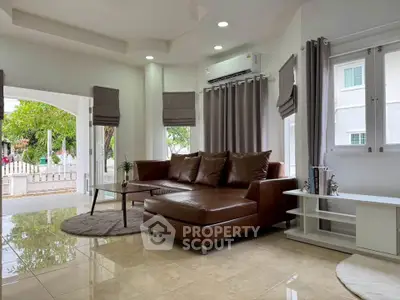 Spacious living room with modern leather sofa and large windows offering natural light.