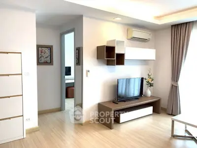 Modern living room with sleek furniture and natural light, featuring a TV unit and air conditioning.