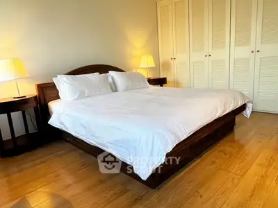 Spacious bedroom with elegant wooden flooring and cozy lighting