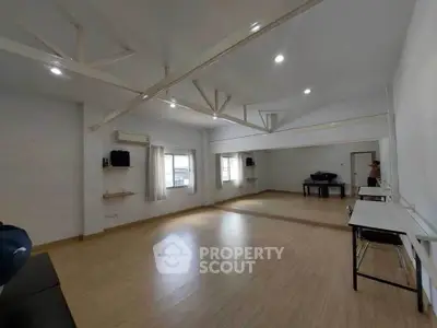 Spacious room with wooden flooring and large mirror, ideal for dance or fitness studio.