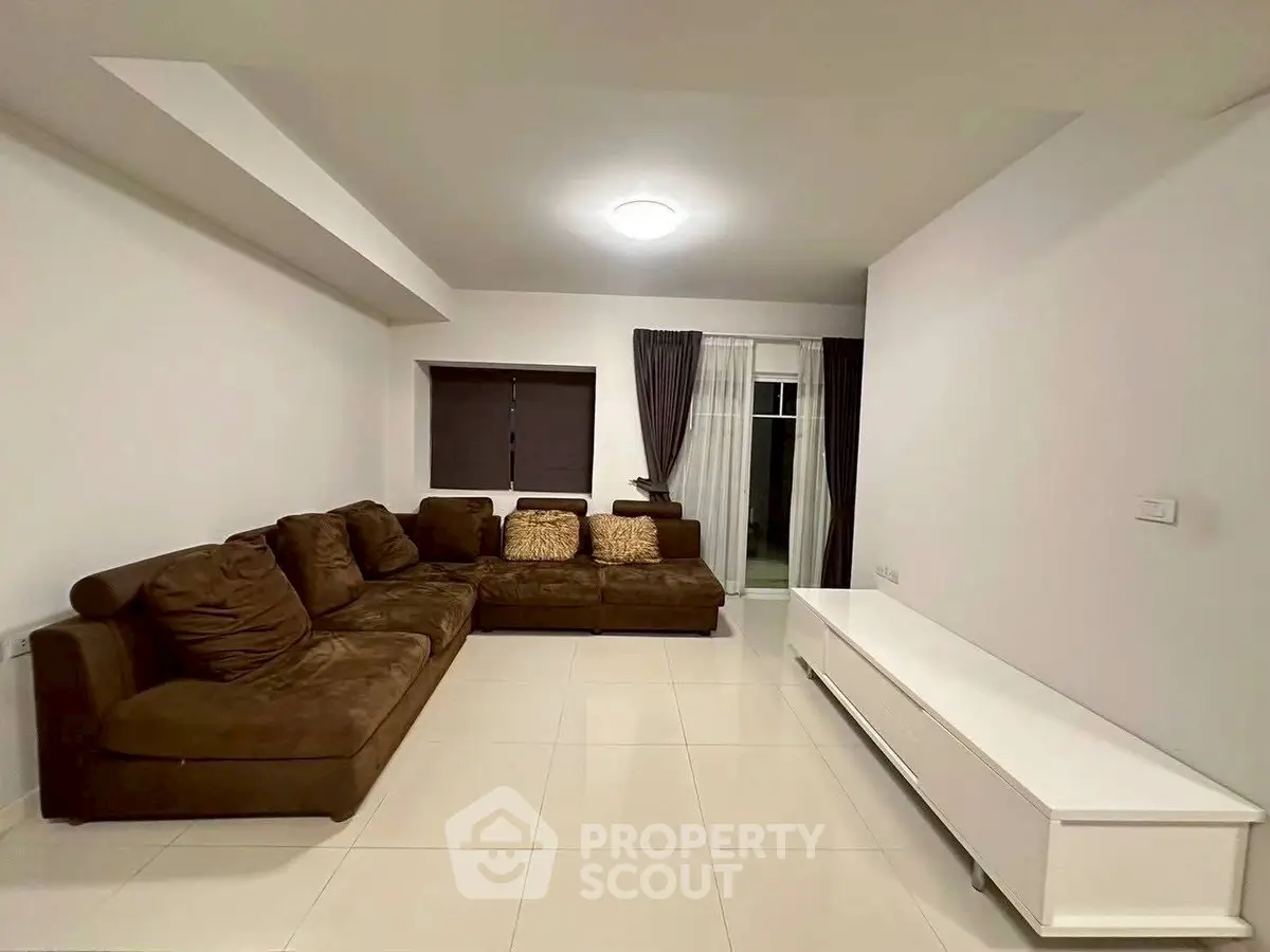 Spacious living room with modern brown sofa and sleek white TV unit.