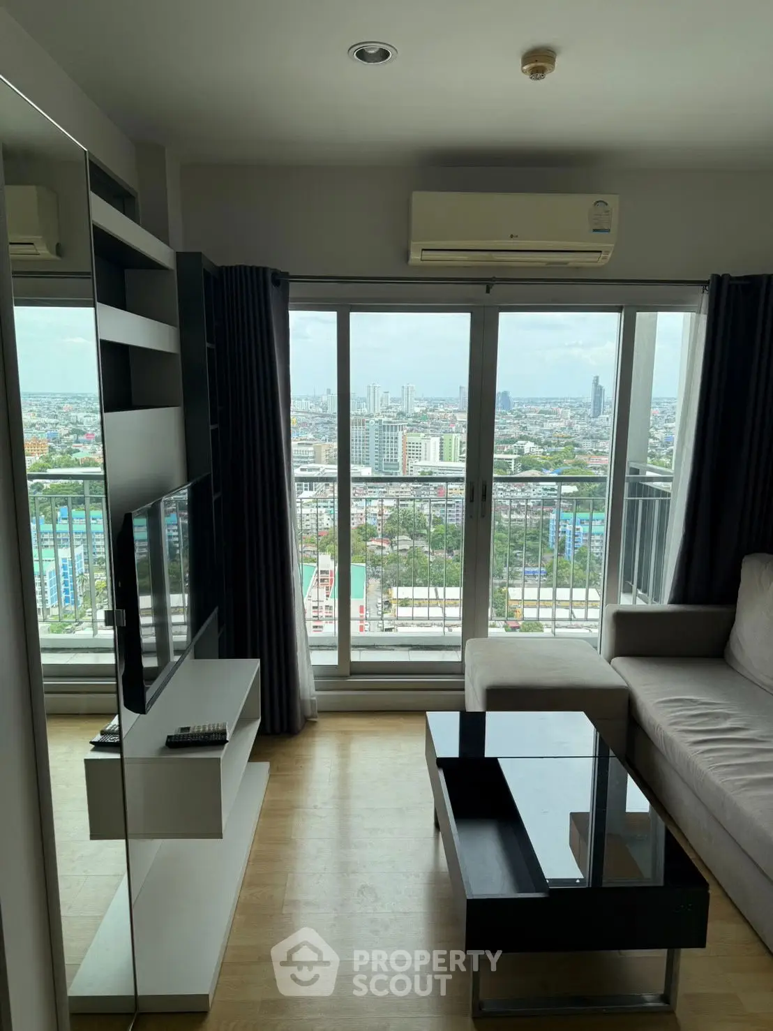 Modern living room with city view, featuring sleek furniture and large windows.