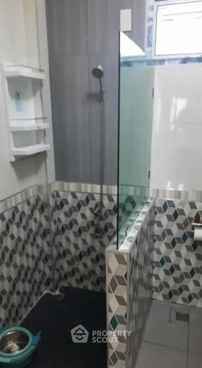 Modern bathroom with geometric tile design and glass shower partition