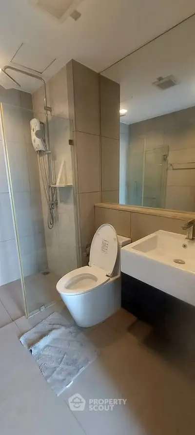 Modern bathroom with sleek fixtures and glass shower enclosure in a contemporary apartment.