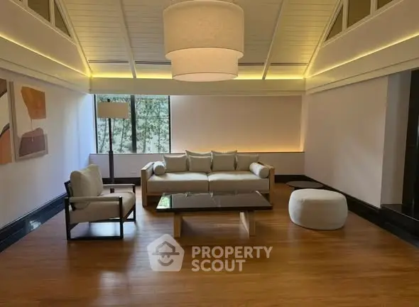 Spacious modern living room with elegant furniture and large windows offering natural light.