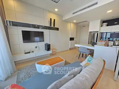 Modern living room with open kitchen, stylish furniture, and built-in TV unit in a contemporary apartment.