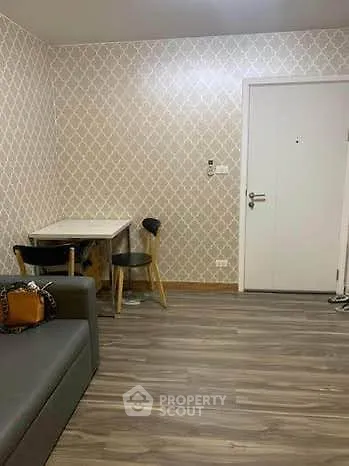 Cozy living room with modern wallpaper and sleek flooring, featuring a compact dining area and stylish seating.