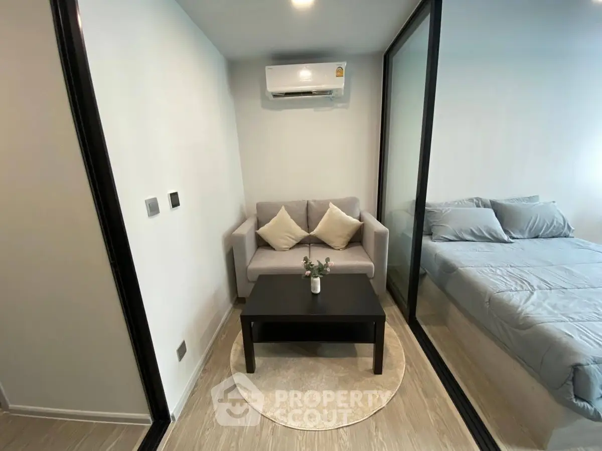 Modern compact living space with cozy sofa and bed, featuring sleek glass partition.