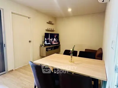 Cozy dining area with modern table and chairs, adjacent to a small entertainment setup in a stylish apartment.