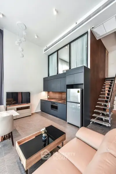 Modern open-plan living room with sleek kitchen and stylish staircase in luxury apartment.