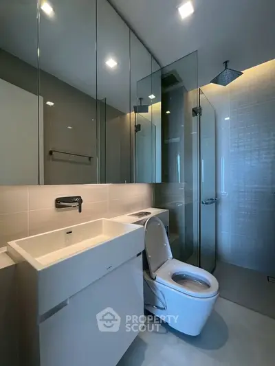 Modern bathroom with sleek fixtures and glass shower enclosure, featuring a contemporary design.