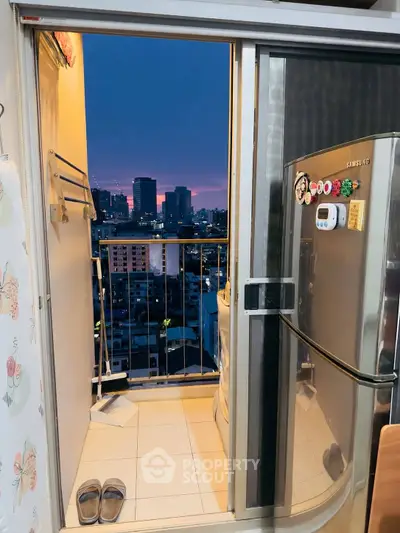 Charming urban balcony with city skyline view and modern fridge, perfect for cozy evenings.