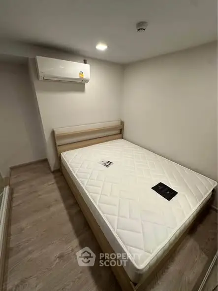 Cozy bedroom with wooden flooring and air conditioning, featuring a comfortable bed.