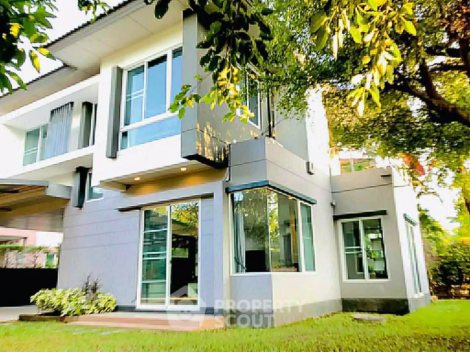 Modern two-story house with large windows and lush greenery