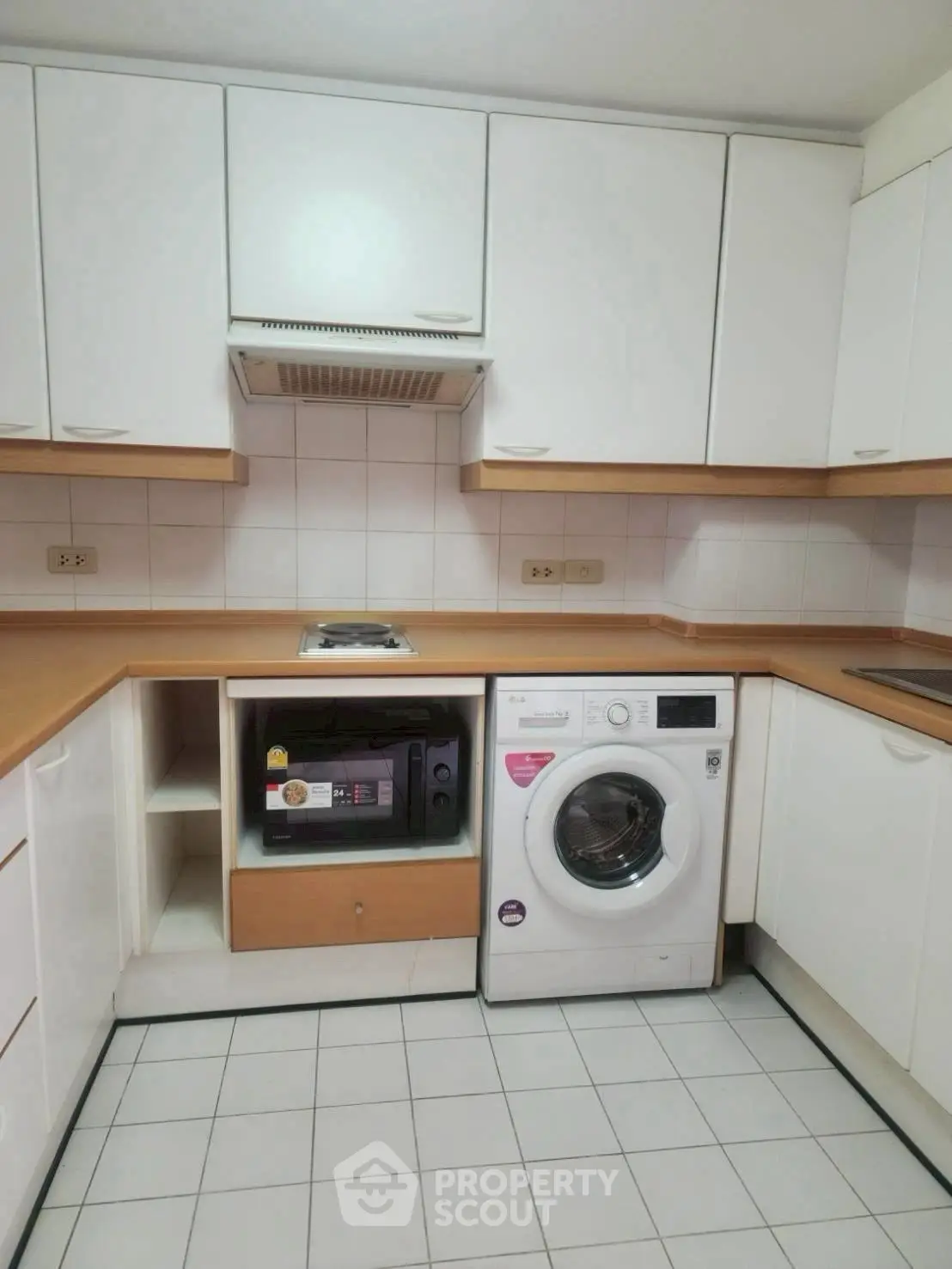 Modern kitchen with washing machine and microwave in sleek cabinetry.