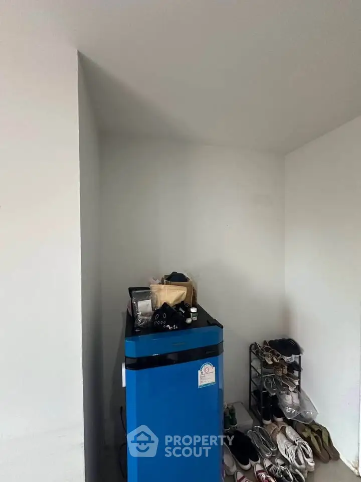 Compact storage area with shoe rack and blue appliance in modern home