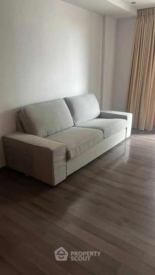 Spacious living room with modern gray sofa and elegant wooden flooring.