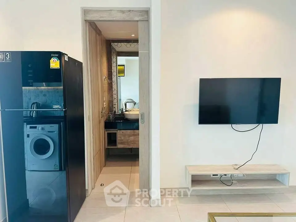 Modern apartment interior with sleek appliances and wall-mounted TV, showcasing a stylish and functional living space.