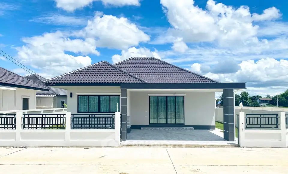 Modern single-story house with sleek design and spacious driveway under a bright blue sky.