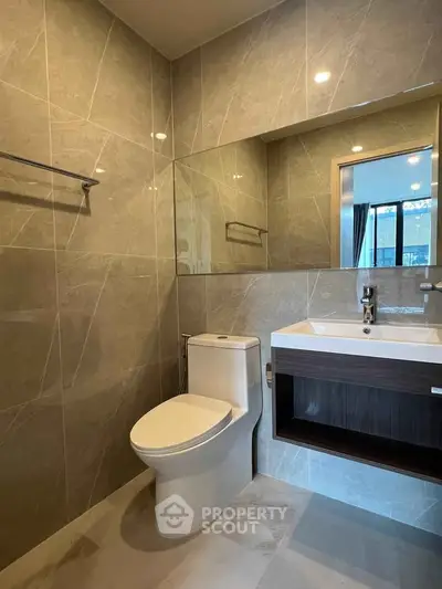 Modern bathroom with sleek fixtures and large mirror in contemporary apartment.