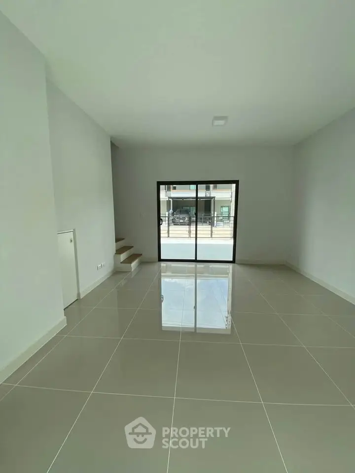 Spacious modern living room with large tiles and sliding glass doors leading to a balcony.