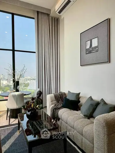Modern living room with large window and stylish decor in a high-rise apartment.