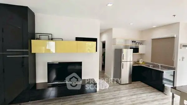 Modern open-layout kitchen and living area with sleek black and yellow cabinetry.