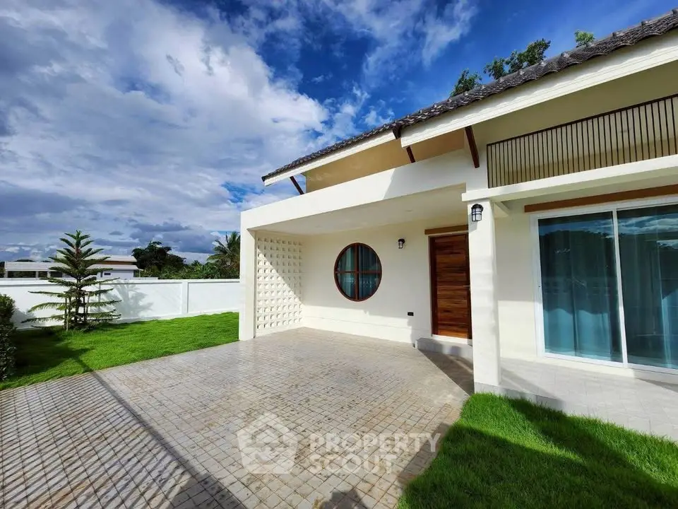Modern single-story house with spacious driveway and lush green lawn under a clear blue sky.