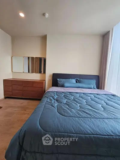Spacious bedroom with modern decor and large window for natural light.