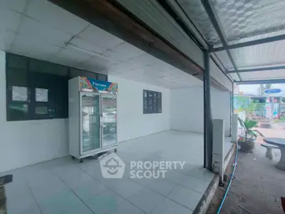Spacious tiled area with refrigerator, ideal for versatile use in commercial or residential property.