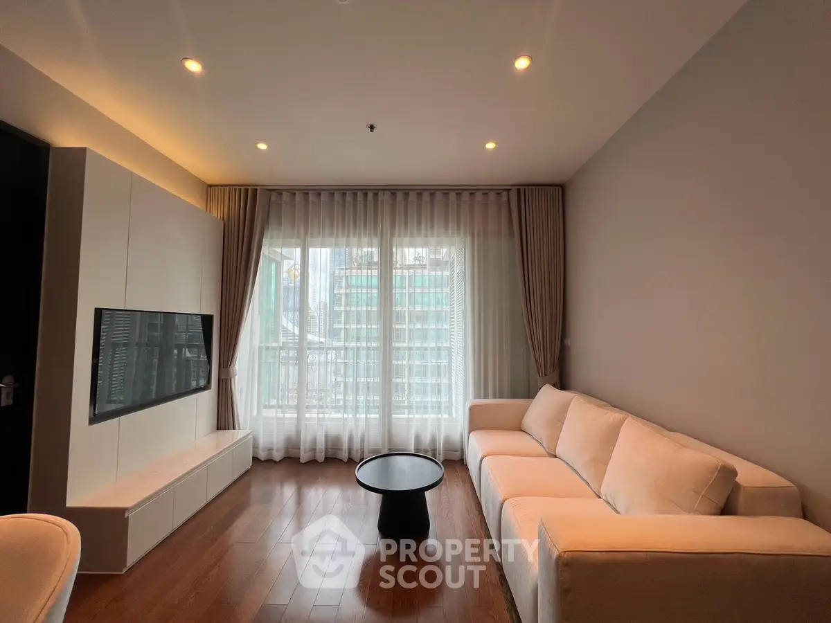 Modern living room with large windows and elegant furnishings in a high-rise apartment.