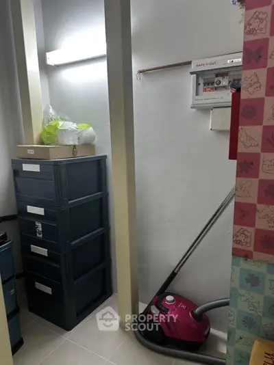 Compact storage room with vacuum cleaner and storage boxes, ideal for organizing household items.