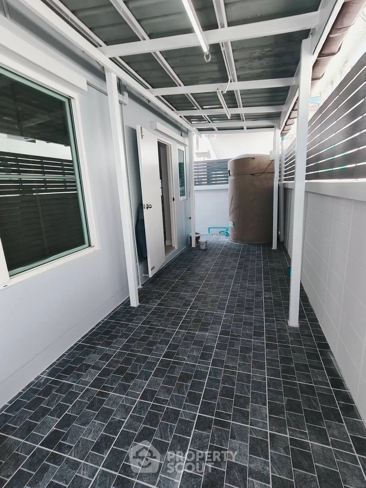 Modern outdoor corridor with tiled flooring and water tank, ideal for utility or storage space.
