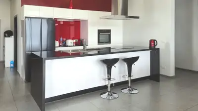 Modern kitchen with sleek black countertops, red accents, and high-end appliances.