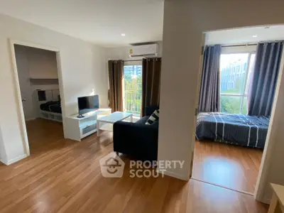Modern apartment with open living room and bedroom, featuring hardwood floors and natural light.