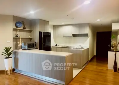 Modern kitchen with sleek cabinetry and wooden flooring in a stylish apartment.