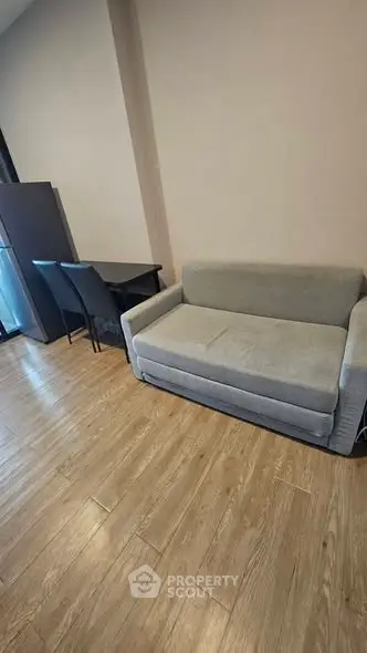 Modern living room with sleek sofa and dining area, featuring elegant wooden flooring.