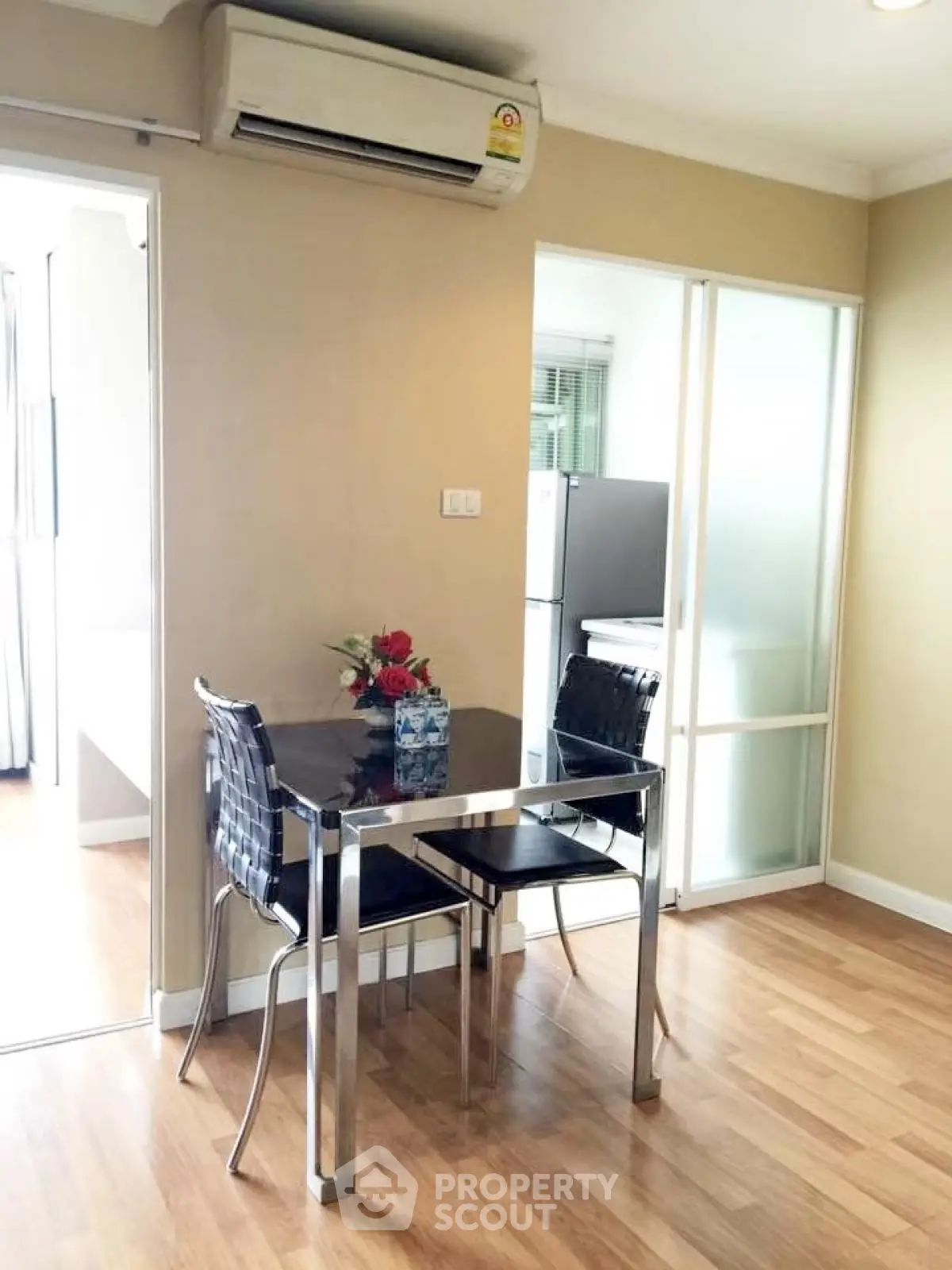 Modern dining area with sleek table and chairs, adjacent to a bright kitchen space.