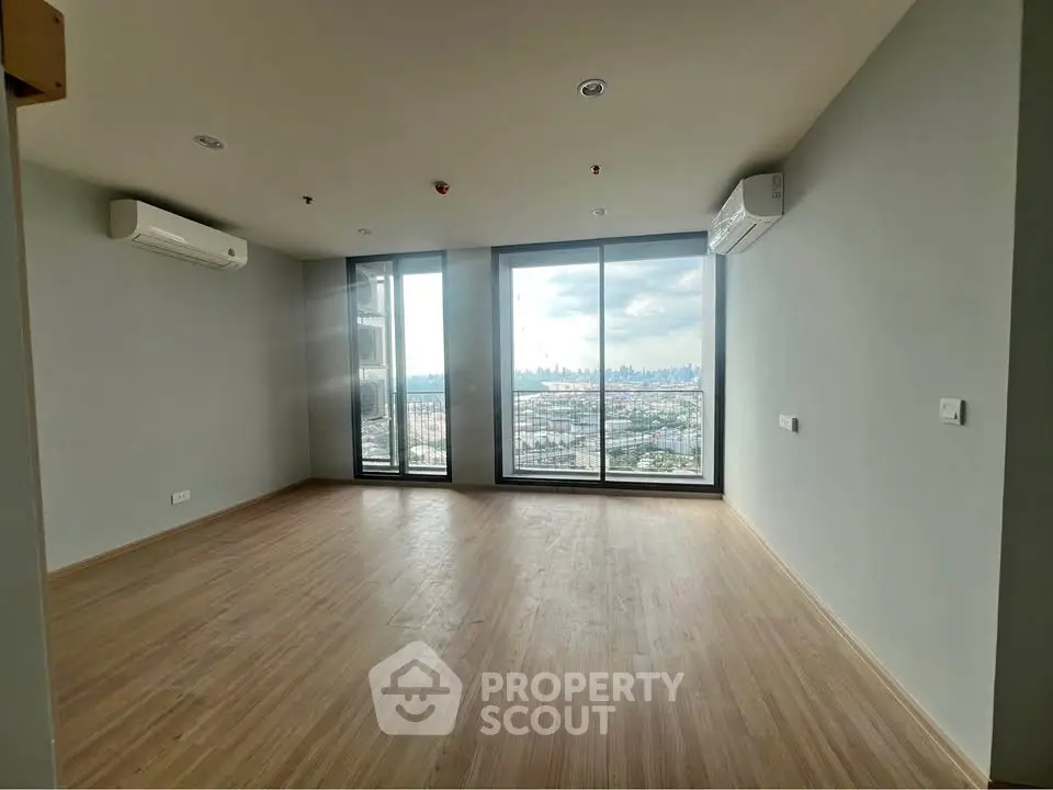 Spacious modern living room with large windows offering stunning city views.