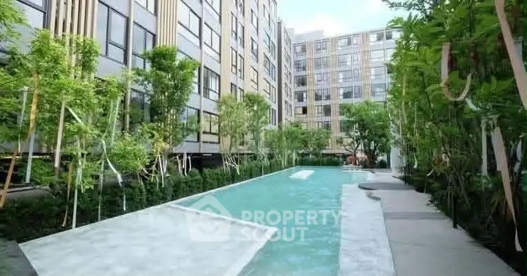 Modern apartment complex with lush greenery and inviting swimming pool.