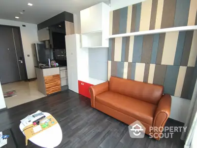 Modern studio apartment with stylish open layout kitchen, cozy living area with a sleek brown leather sofa, and vibrant accent wall.