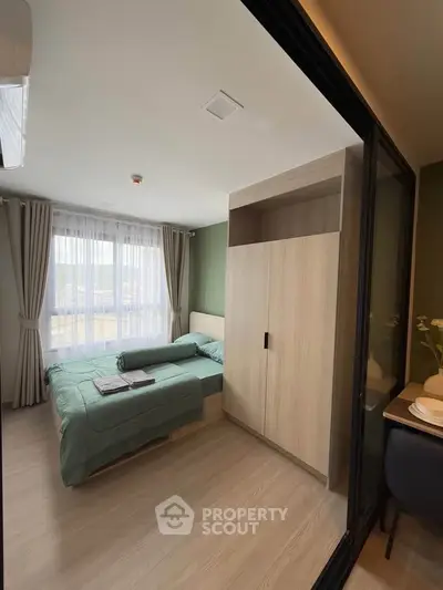 Modern bedroom with large window and stylish decor in a cozy apartment.