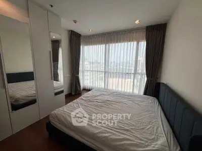 Spacious bedroom with large windows and modern furnishings in a high-rise apartment.