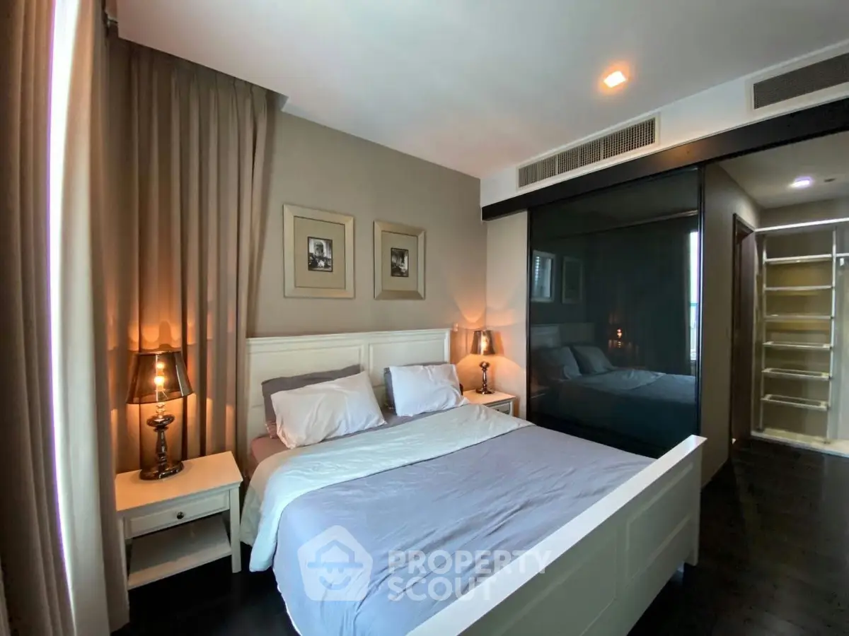 Elegant bedroom with modern decor and ample natural light, featuring a cozy bed and stylish lighting.