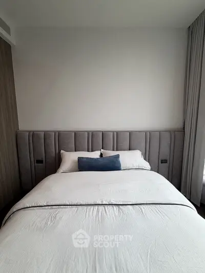 Luxurious bedroom with plush headboard and elegant bedding in modern apartment.