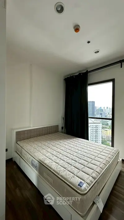 Spacious bedroom with city view and large window, featuring a comfortable mattress and modern design.